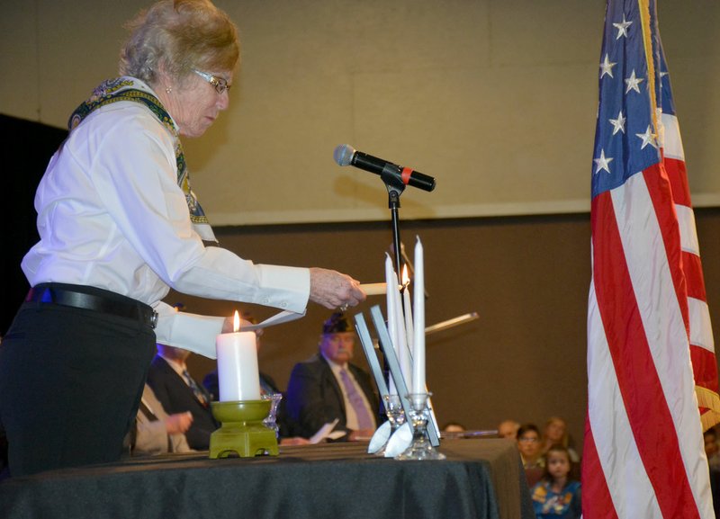 Hunter McFerrin/Herald-Leader The American Legion Siloam Post 29 held the second annual Four Chaplains Memorial Service on Sunday afternoon, where veterans, along with their friends and family gathered to honor the lives of four military chaplains and over 600 servicemen who lost their lives during World War II. Above, Carol Smith of the Post 29 Auxiliary Unit lights the first of four candles that were lit and each represented one of the four chaplains. Afterwards, she gave a brief address that included some biographical information on the chaplain she represented.