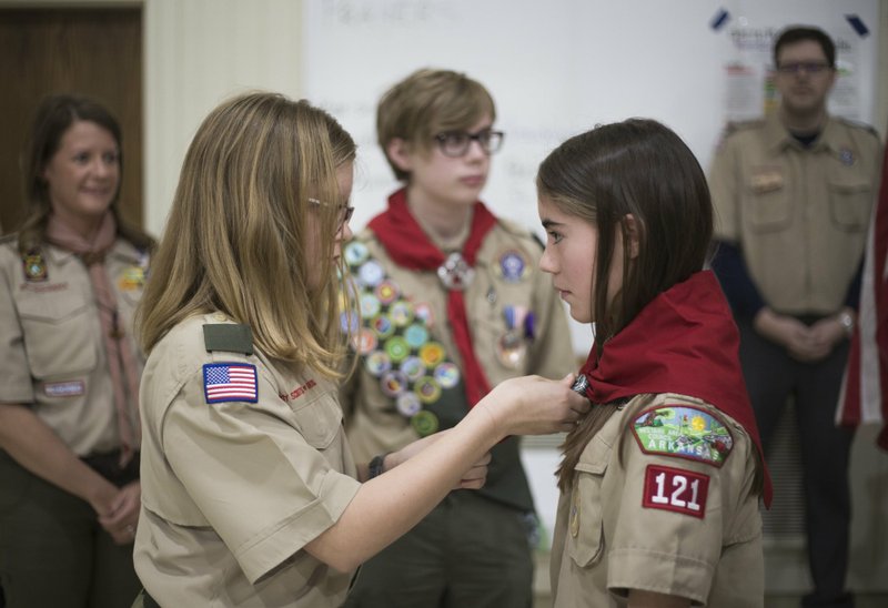 NWA Democrat-Gazette/CHARLIE KAIJO Annabella Rose Tyburski (left) wraps a Scouts neckerchief around Ruby Freeman (right) during a crossover ceremony Feb. 2 at the First Presbyterian Church in Bentonville.