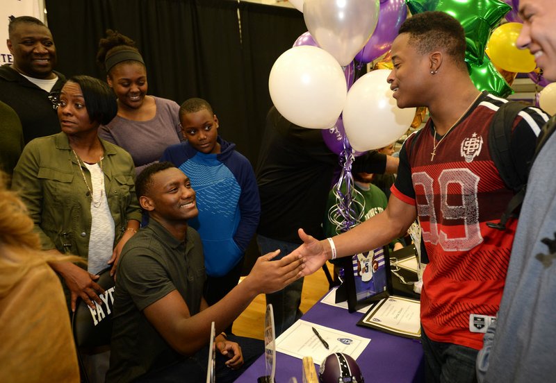 NWA Democrat-Gazette/ANDY SHUPE Fayetteville quarterback Darius Bowers (left) is congratulated Wednesday, Feb. 6, 2019, by friend Radarian Cobbs after Bowers signed to play football with the University of Central Arkansas during a signing ceremony at Fayetteville High School.