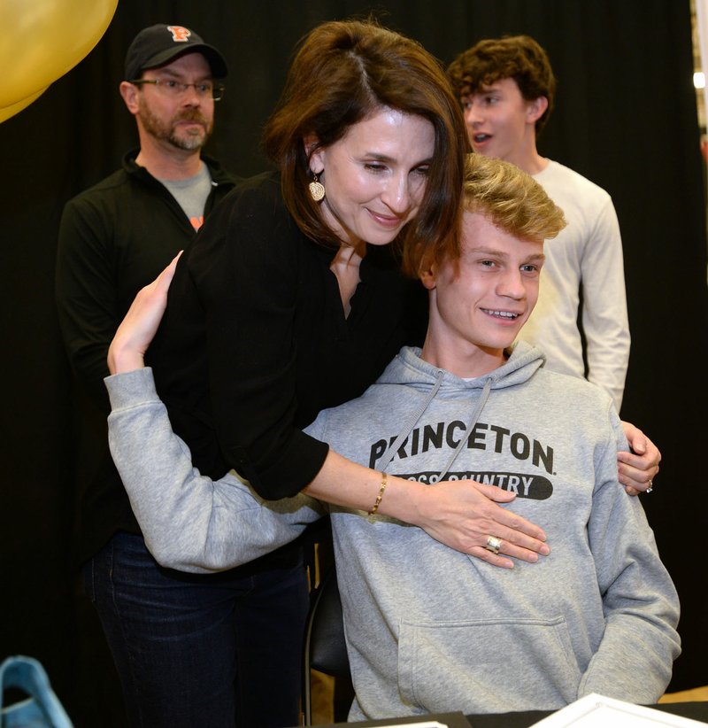 NWA Democrat-Gazette/ANDY SHUPE Fayetteville cross country and track and field runner Camren Fischer (right) gets a hug Wednesday, Feb. 6, 2019, from his mother, Kim, as his father, Tim, and brother, Samuel, stand behind after Camren signed to run for Princeton during a signing ceremony at Fayetteville High School.