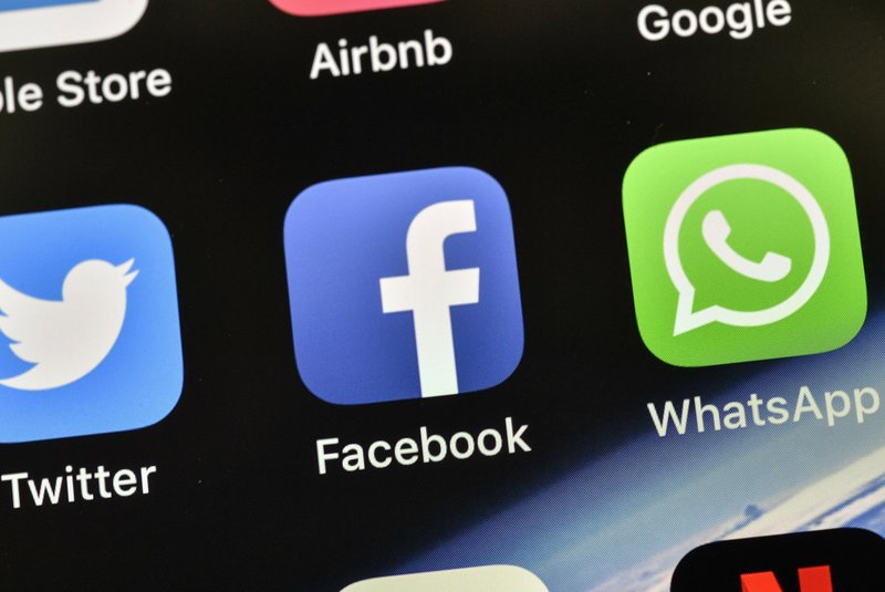 In this Thursday, Nov. 15, 2018 file photo the icons of Facebook and WhatsApp are pictured on an iPhone in Gelsenkirchen, Germany. German antitrust authorities have issued a ruling prohibiting Facebook from combining user data from different sources. (AP Photo/Martin Meissner)