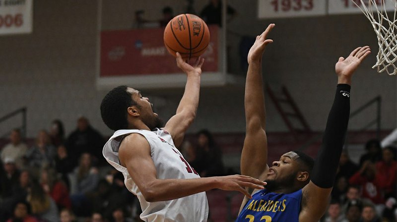 Southern Arkansas’ Wesley Nosakhare defends a shot by Henderson State’s Raekwon Rogers during GAC basketball action Thursday night. The Reddies got revenge from an earlier loss to SAU by beating the Muleriders by 19 points. Photo credit: HSU Sports