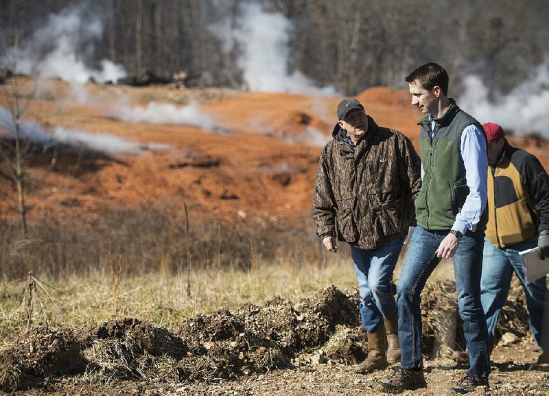 Kevin White (left), associate director of land resources with the Arkansas Department of Environmental Quality, leads Arkansas’ U.S. Sen. Tom Cotton and others on a tour Friday at the stump dump fi re site in Bella Vista. 