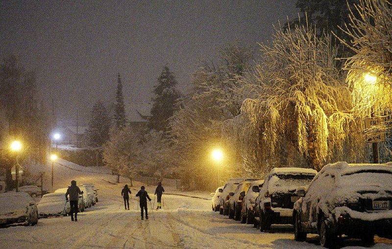 People use skis to get around Friday io an icy street in Tacoma, Wash. More than a foot of snow was reported in some areas. 