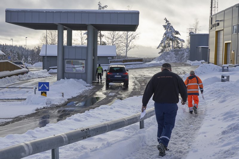 Truck drivers with customs clearance documents walk towards the Norwegian Customs office at the Orje border as officers perform checks on cars entering from Sweden, on Friday, Feb. 8 2019. Vehicles entering Norway are randomly checked, with officers mainly looking for alcohol and cigarettes which are cheaper in Sweden. Norway's hard border with the European Union is equipped with cameras, license-plate recognition systems and barriers directing traffic to Customs officers. (AP Photo/David Keyton)