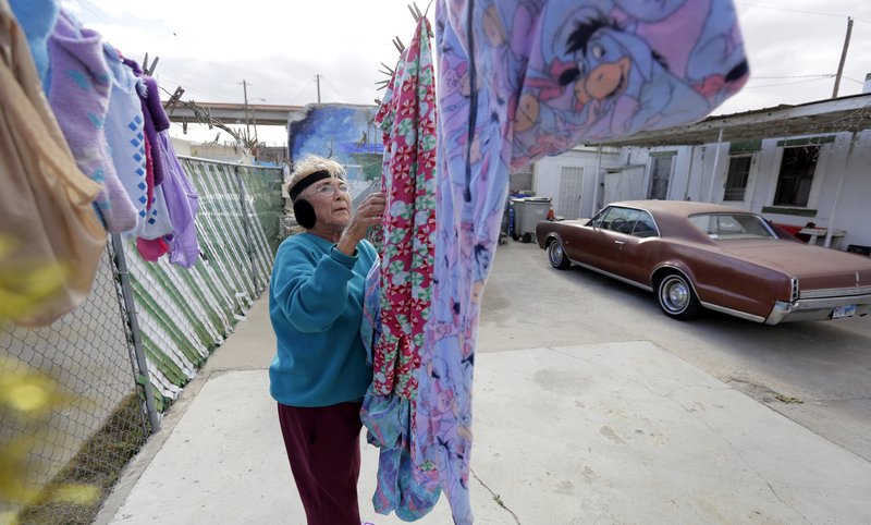 In this Tuesday, Jan. 22, 2019, photo, Mickie Subia gathers her laundry at her home in El Paso, Texas. Subia lives less than a block away from a border barrier that runs along the Texas-Mexico border in El Paso. (AP Photo/Eric Gay)