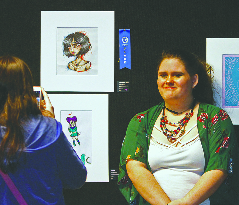 Reception: Parkers Chapel ninth grader Carey Haynes poses for a photo next to her artwork during the South Arkansas Arts Center artist reception for 2019 SAAC Student Art Competition on Saturday. Haynes' mixed media art piece titled "Welcome to Seoul" placed first in its category.
