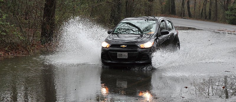  WATER COVERED ROAD: Water sprays into the air as a car drives through pooling water in the 2100 block of Sleepy Valley Road.