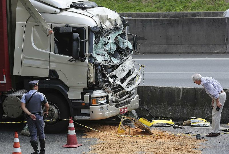 A man looks at wreckage after a helicopter crashed into the front of a cargo truck Monday during an emergency landing, on a main highway in Sao Paulo, Brazil. 66-year-old Brazilian television news anchor Ricardo Boechat and the pilot perished in the accident. Police say the truck driver suffered only minor injuries. 