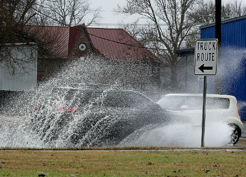 Cars splash through standing water on West Broadway after heavy rainfall in North Little Rock on Monday morning. Officials said as much as two inches of rain fell in parts of central Arkansas on Monday, with more expected overnight. 