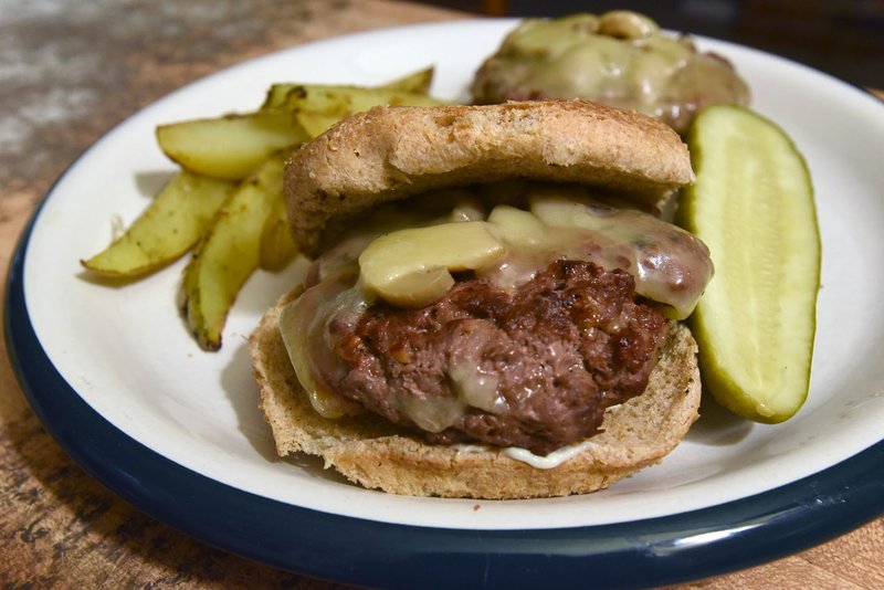 NWA Democrat-Gazette/FLIP PUTTHOFF 
Mushroom and swiss venison burger is a Camp See No Deer favorite. It's delicious with or without the toasted bun. Served with grilled steak fries and a crisp dill pickle, it's a meal that'll satisfy any hungry hunter.