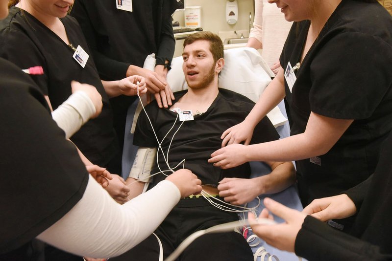 NWA Democrat-Gazette/FLIP PUTTHOFF Moe Abdin (center), a Bentonville High School student in the Ignite Professional Studies program, acts Tuesday as a patient while other students take his blood pressure, pulse and other readings at Northwest Medical Center-Bentonville.