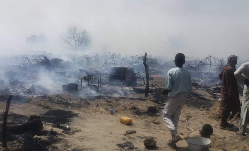 ADVANCE FOR PUBLICATION ON WEDNESDAY, FEB. 13, AND THEREAFTER - In this photo taken Thursday, Feb. 7, 2019, and provided by the International Rescue Committee (IRC), internally-displaced persons look at destroyed houses following a fire at a camp for those who had fled fighting in surrounding areas, in Monguno town, Borno State, northeastern Nigeria. Nigeria's government acknowledges an extremist resurgence by Boko Haram offshoot in the Islamic State West Africa Province, and the renewed extremist violence may threaten the validity of upcoming Saturday's election in the northeast. (Deborah Peter/International Rescue Committee via AP)