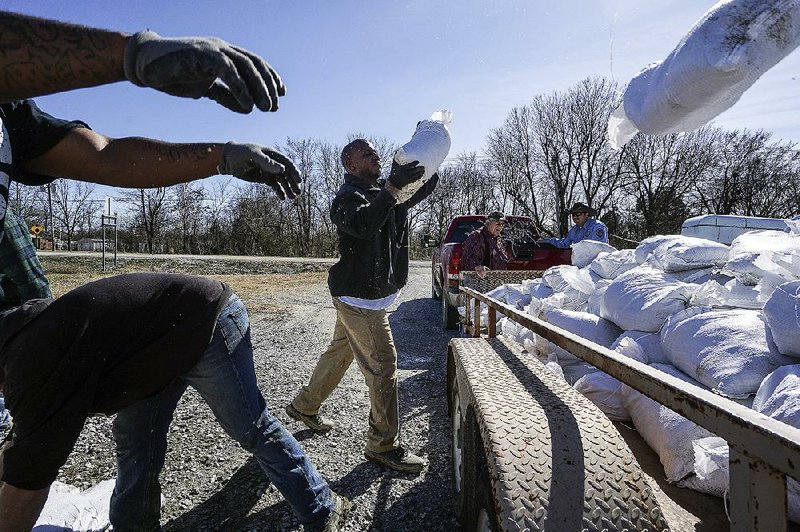 Chris Harris (center) and others load sandbags on a trailer Wednesday at the Erwin Fire Station in Newport as people in Jackson and Woodruff counties take precautions in the event a deteriorating levee near Newport gives way to rising water from the White River after days of heavy rain. Jeff Phillips, county judge of Jackson County, issued an evacuation warning Tuesday night to residents of about 30 homes that sit below the levee. 