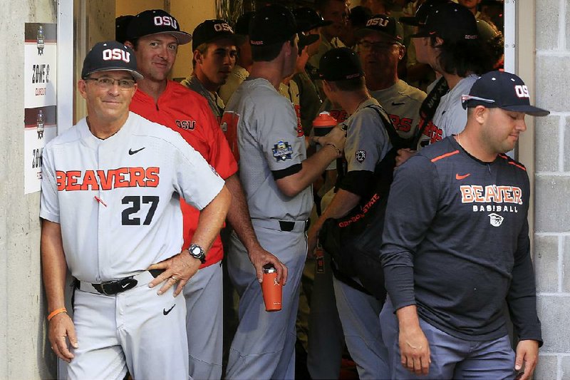 In this June 18, 2018, photo, then-Oregon State associate head coach Pat Bailey (27) stands in the tunnel with players before an NCAA College World Series baseball game, in Omaha, Neb. Bailey, now Oregon State's interim head coach, is taking over the program that won the 2018 national championship and 111 of its last 130 baseball games. 