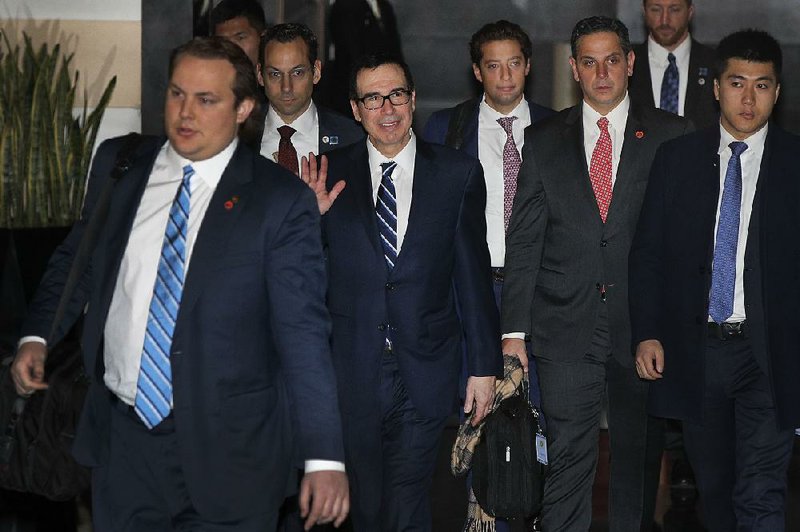 U.S. Treasury Secretary Steven Mnuchin (center) waves to journalists Wednesday, as he and part of his trade delegation leave a hotel in Beijing, where he and U.S. Trade Representative Robert Lighthizer will begin high-level trade talks with China today. 