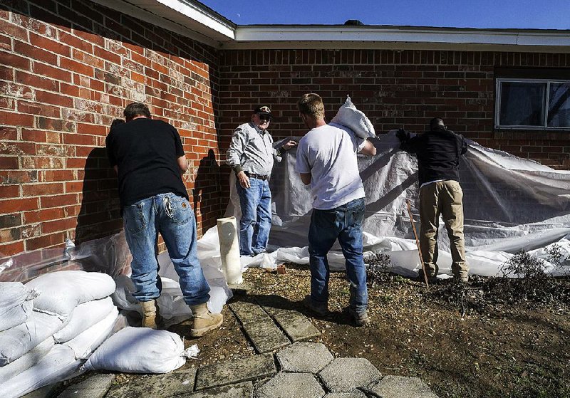 Ron Bullock (second from left), brother-in-law of homeowner Robert Gilliaum, guides help Wednesday as sandbags are positioned at the home in Jackson County. It’s the first time in more than 50 years that such protection has been required because of the threat of flooding.