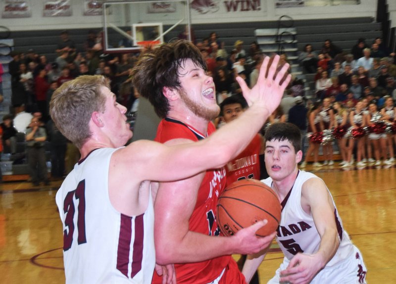 RICK PECK/SPECIAL TO MCDONALD COUNTY PRESS McDonald County's Cooper Reece gets past Nevada's Dalton Gayman (31) and Logan McNeley (5) to score two of his game-high 26 points in the Mustangs' 62-52 loss to Nevada on Feb. 8 at Nevada High School.