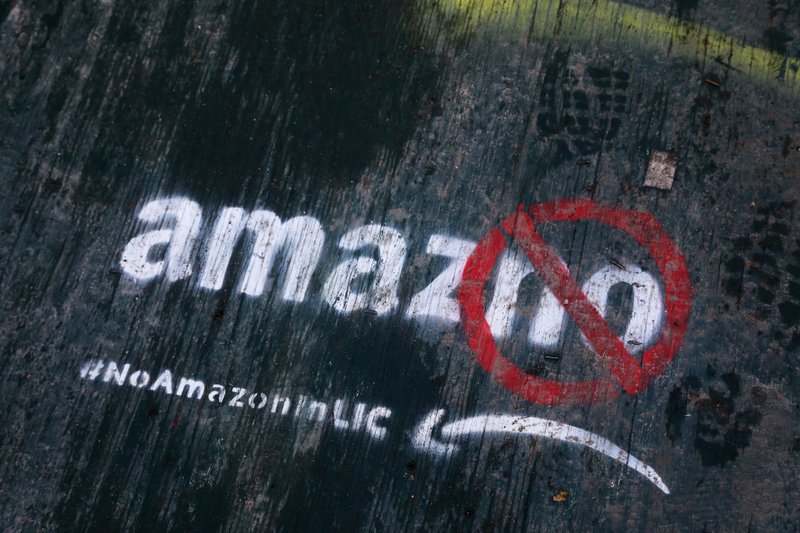 FILE- In this Nov. 16, 2018, file photo graffiti has been painted on a sidewalk by someone opposed to the location of an Amazon headquarters in the Long Island City neighborhood in the Queens borough of New York. Amazon said Thursday, Feb. 14, 2019, that it is dropping New York City as one of its new headquarter locations. (AP Photo/Mark Lennihan, File)

