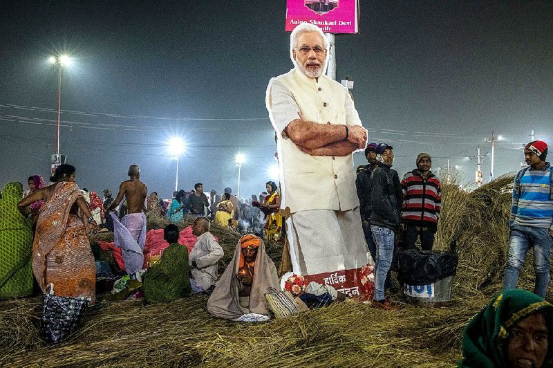 A cardboard cutout of Prime Minister Narendra Modi of India stands among attendees of the Kumbh Mela religious festival in India. The festival has been even bigger this year, infused with the governing party’s cash and advertisements during high campaign season. 