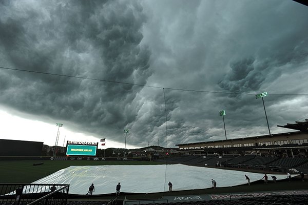 Volunteers pull a tarp over the infield on Friday, May 19, 2017, at Baum Stadium in Fayetteville. 