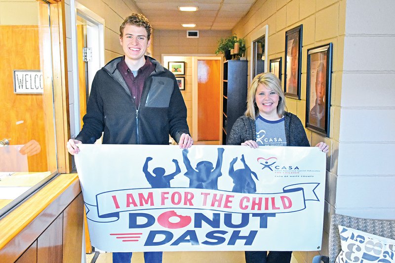 Parker Samuel, left, and Laura Burks hold a banner advertising the upcoming Donut Dash for Court Appointed Special Advocates of White County. The Donut Dash will be March 2 at Bison Park at Harding University in Searcy.