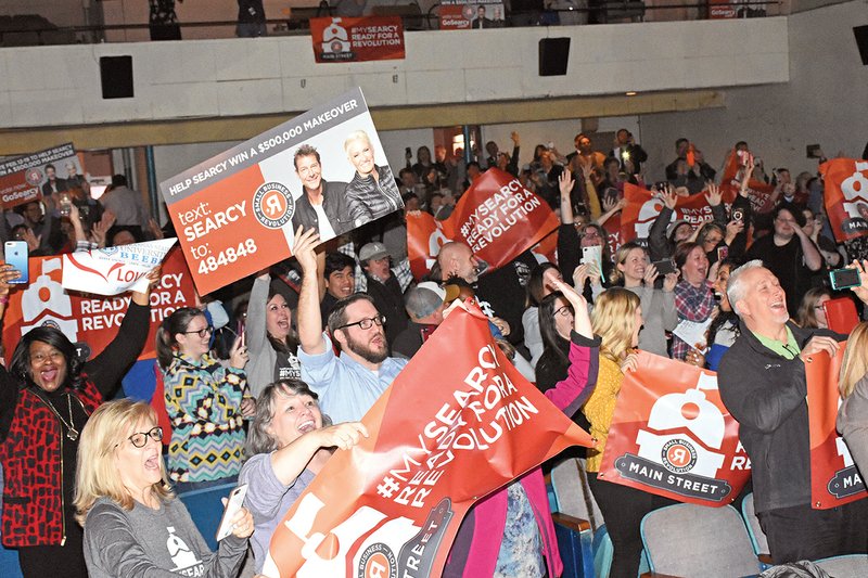 In front, from left, Kary Ross, Terri Kellar and Wendy Neill (behind the banner), all of Searcy, and other audience members react to the announcement of Searcy making it to the top six towns to be featured on Small Business Revolution-Main Street. The watch party was held Tuesday in the Rialto Theater, where attendants could watch the Facebook Live announcement on the big screen.