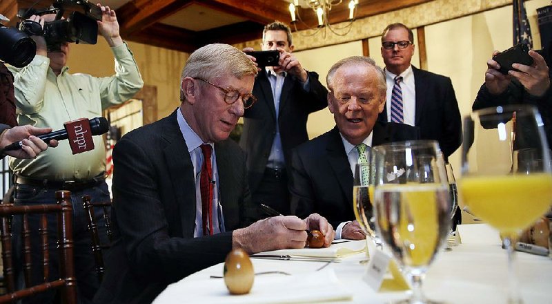 Former Massachusetts Gov. William Weld signs wooden egg keepsakes during a political event Friday in Bedford, N.H. 