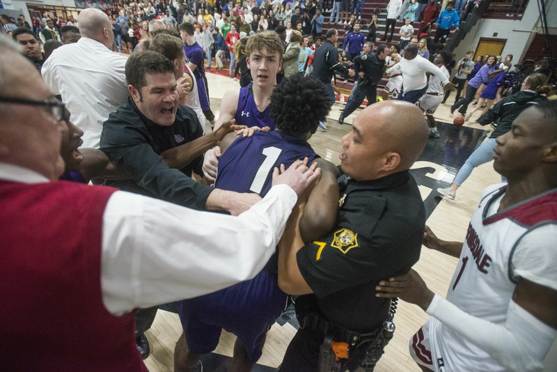NWA Democrat-Gazette/BEN GOFF @NWABENGOFF Brad Stamps, Fayetteville assistant coach, and Springdale police officer Gomez Zackious hold back Austin Garrett (1) of Fayetteville while breaking up a brawl on the court Friday, Feb. 15, 2019, during the game at Springdale's Bulldog Gym.