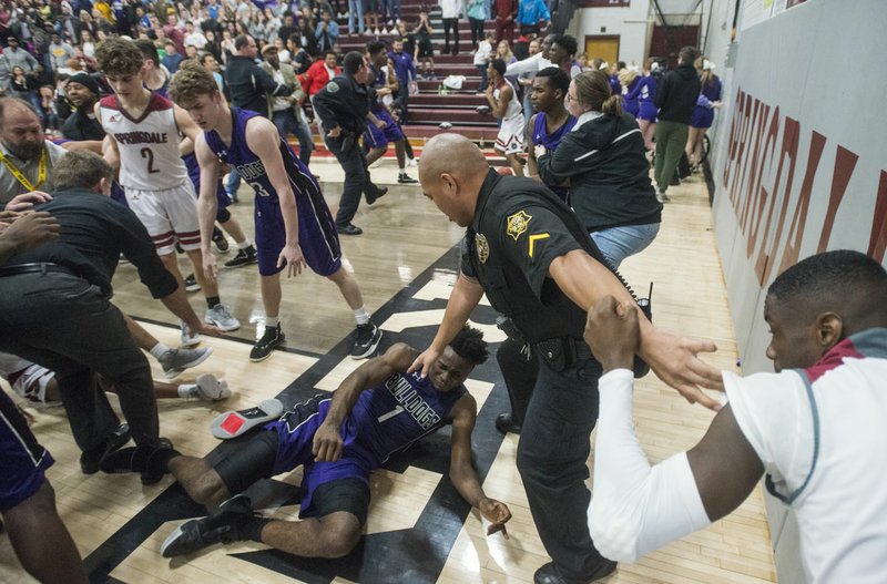 NWA Democrat-Gazette/BEN GOFF @NWABENGOFF Springdale police officer Gomez Zackious breaks up Austin Garrett (1) of Fayetteville and Jajuan Boyd (right) of Springdale during a brawl on the court Friday, Feb. 15, 2019, during the game at Springdale's Bulldog Gym.