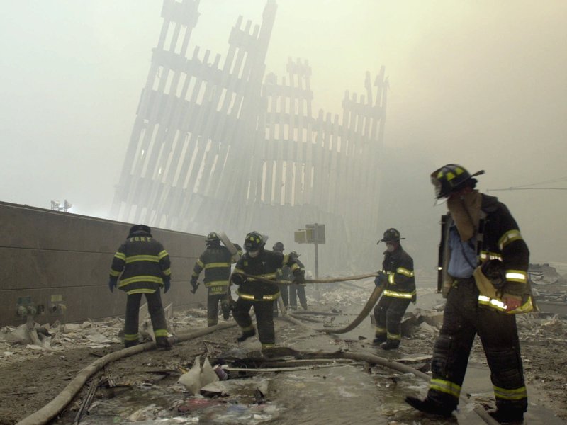 FILE - In this Sept. 11, 2001 file photo, with the skeleton of the World Trade Center twin towers in the background, New York City firefighters work amid debris on Cortlandt St. after the terrorist attacks. On Friday, Feb. 15, 2019, Rupa Bhattacharyya, the September 11th Victim Compensation Fund special master, announced that the compensation fund for victims of the Sept. 11, 2001 terror attacks will cut future payments by 50 to 70 percent because the fund is running out of money. (AP Photo/Mark Lennihan, File)