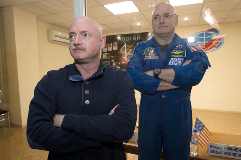 FILE - In this March 26, 2015 file photo, U.S. astronaut Scott Kelly, right, crew member of the mission to the International Space Station, stands behind glass in a quarantine room, behind his brother, Mark Kelly, also an astronaut, after a news conference in the Russian-leased Baikonur, Kazakhstan cosmodrome. Nearly a year in space put Scott Kelly's immune system on high alert and changed the activity of some of his genes compared to his Earth-bound identical twin, according to a report released on Friday, Feb. 15, 2019. (AP Photo/Dmitry Lovetsky)