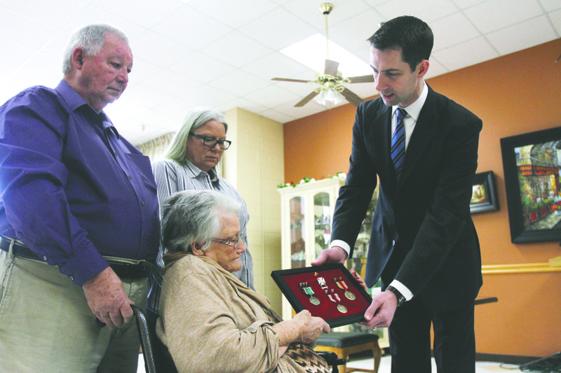 Presentation: Above, U.S. Sen. Tom Cotton-R, presents medals to Helen Hicks, seated, accompanied by her son Bob, and daughter Vickie Porter at Hudson Memorial Nursing Home Saturday morning. The medals, which belong to Helen's husband Cpl. Robert Hicks, a D-Day veteran, were replaced with efforts made by Cotton's office after the originals were destroyed in a house fire. Below left, Hicks looks at her husband’s military medals. Terrance Armstard/News-Times