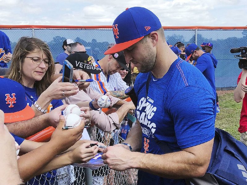 Tim Tebow signs autographs at a spring training practice with the New York Mets on Saturday in Port St. Lucie, Fla. 