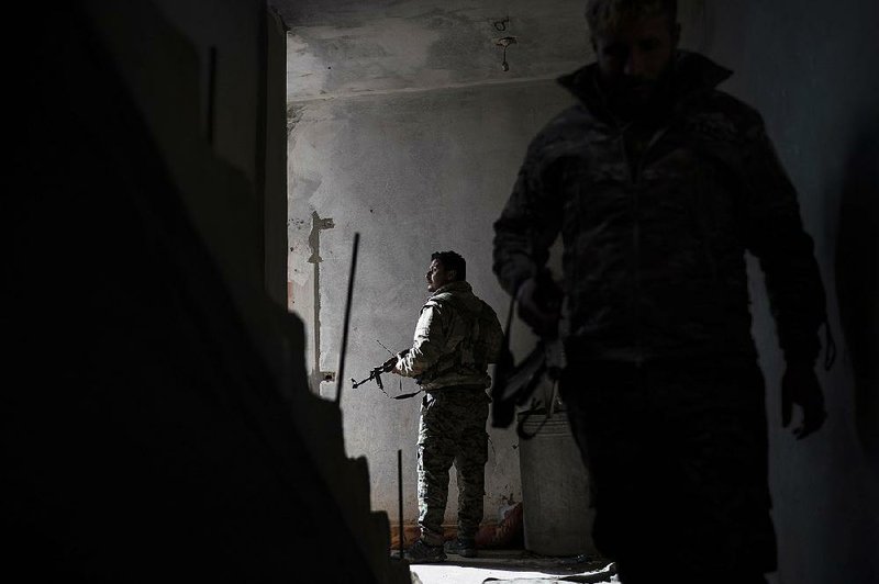 Members of the U.S.-backed Syrian Democratic Forces walk through a building Saturday as they battle Islamic State militants in Baghouz, Syria. 