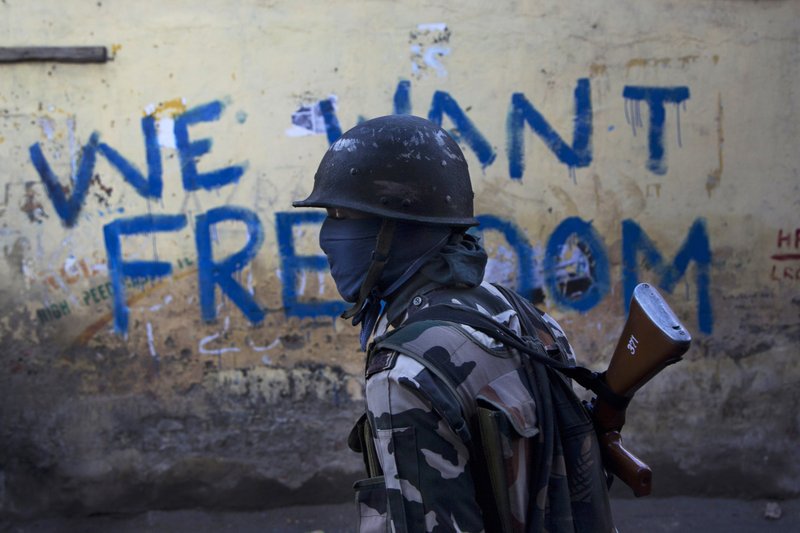 FILE- In this Aug. 29, 2016 file photo, an Indian paramilitary soldier walks past graffiti on a wall in Srinagar, Indian-controlled Kashmir. As India considers its response to the suicide car bombing of a paramilitary convoy in Kashmir that killed dozens of soldiers on Feb. 14, 2019, a retired military commander who oversaw a much-lauded military strike against neighboring Pakistan in 2016 has urged caution. (AP Photo/Dar Yasin, File)