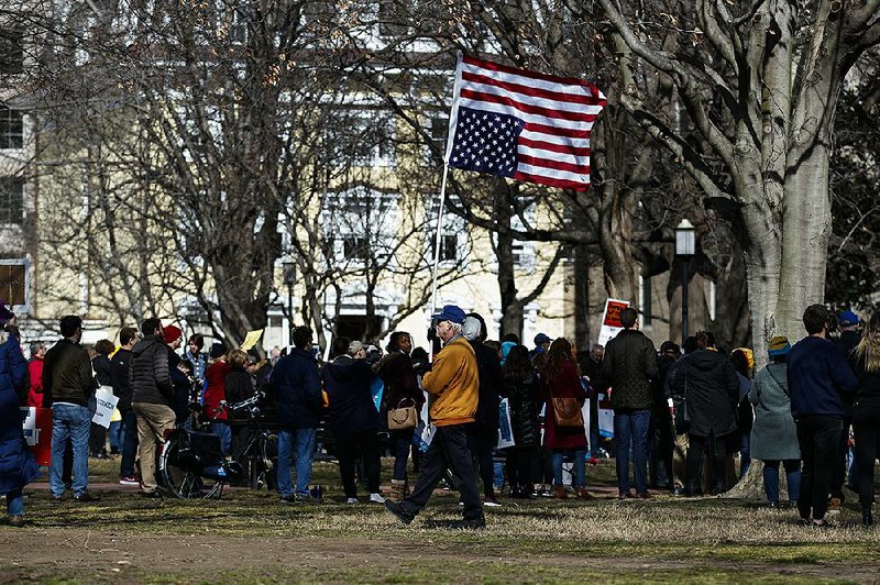 A man walks with an American flag upside down during a protest Monday in Lafayette Square in front of the White House in Washington, to protest that President Donald Trump declared a national emergency along the southern border. 