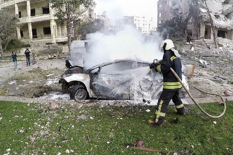 This photo released Monday by the Syrian Civil Defense group known as the White Helmets, shows Syrian White Helmet civil defense workers putting out a fire at the site of twin explosions, in the northwestern city of Idlib, Syria. 