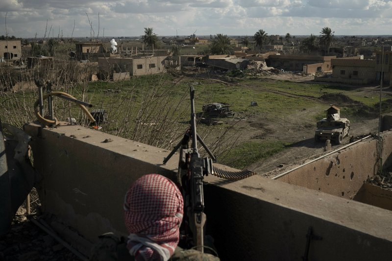 A U.S.-backed Syrian Democratic Forces (SDF) fighter stands atop a building used as a temporary base near the last land still held by Islamic State militants in Baghouz, Syria, Monday, Feb. 18, 2019. Hundreds of Islamic State militants are surrounded in a tiny area in eastern Syria are refusing to surrender and are trying to negotiate an exit, Syrian activists and a person close to the negotiations said Monday. (AP Photo/Felipe Dana)