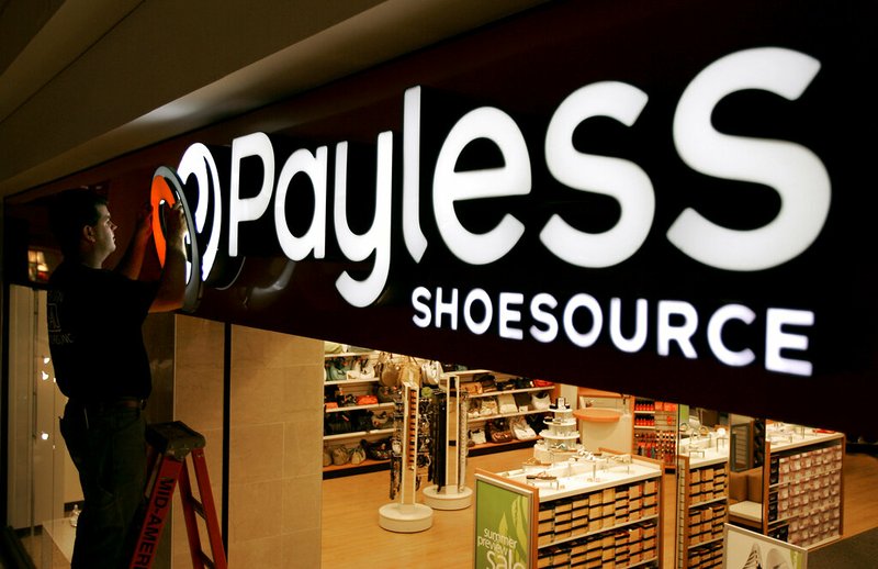 In this May 18, 2006, file photo a worker puts the finishing touches on a sign unveiling the company's new look at a Payless Shoesource store at a mall in Independence, Mo. Payless ShoeSource has filed for Chapter 11 bankruptcy protection and is shuttering its remaining stores in North America. The filing on Monday, Feb. 18, 2019, came a day after the shoe chain began holding going-out-of-business sales at its North American stores. (AP Photo/Charlie Riedel, File)