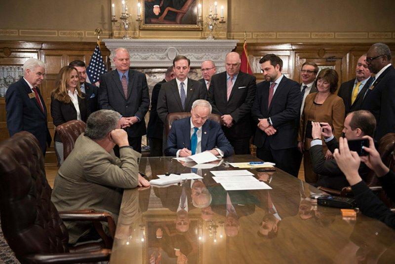 Gov. Asa Hutchinson (seated, middle) signs SB 211 into law Tuesday. 