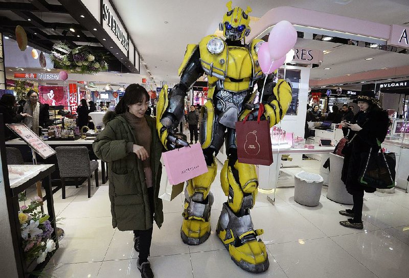 A person dressed as the Transformers action figure Bumblebee helps a woman carry bags last week at a shopping mall in Handan, China. U.S. and Chinese officials resumed trade talks Tuesday in Washington. 