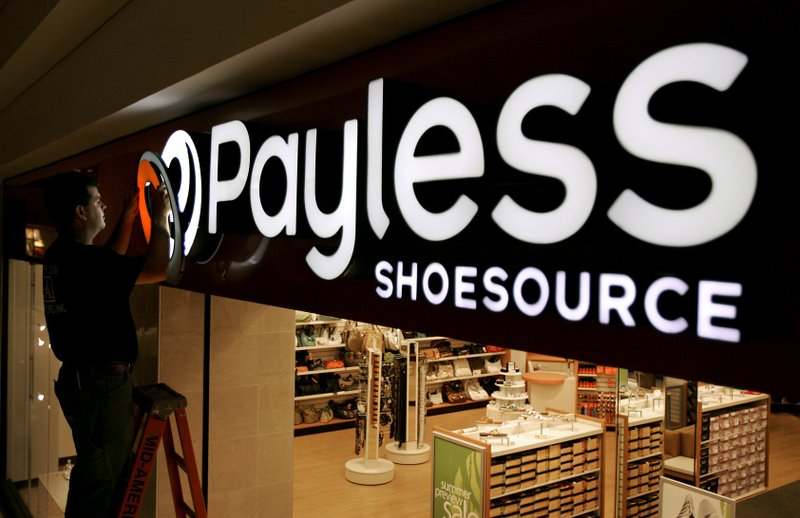 In this May 18, 2006, file photo a worker puts the finishing touches on a sign unveiling the company's new look at a Payless Shoesource store at a mall in Independence, Mo. 