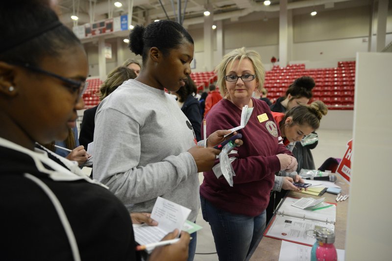 Kim Hunter (right) of Ray & Associates Real Estate in Magnolia helps MHS seniors with home mortgage tips during a Wednesday, Feb. 20, financial planning program at Panther Arena.