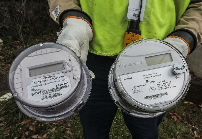 Michael Carter with contractor Scope Services installs smart meters Thursday on a house in Little Rock as part of Entergy Arkansas’ project to install new devices for its 700,000 customers. 