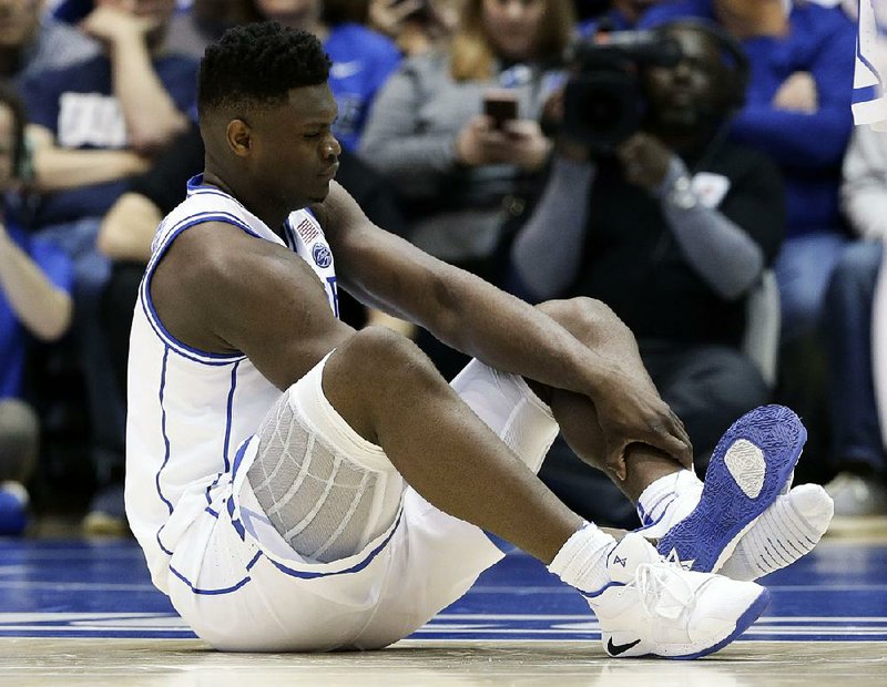 Duke’s Zion Williamson sits on the floor after spraining his right knee when his shoe blew out 36 seconds into the top-ranked Blue Devils’ loss to No. 8 North Carolina on Wednesday.