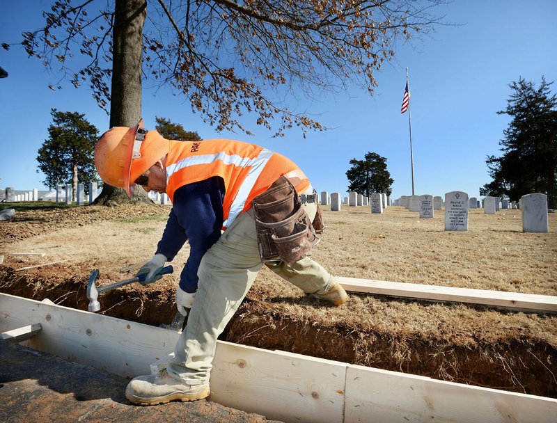 File photo/NWA Democrat-Gazette/ANDY SHUPE Adrian Medina, a worker with PaveCon, assembles a concrete form on Feb. 12 while working to replace a curb along the circle drive at the center of the Fayetteville National Cemetery. The work is part of planned improvements to the cemetery that include parking lot expansion and the replacement of the curb surrounding the center circle drive.