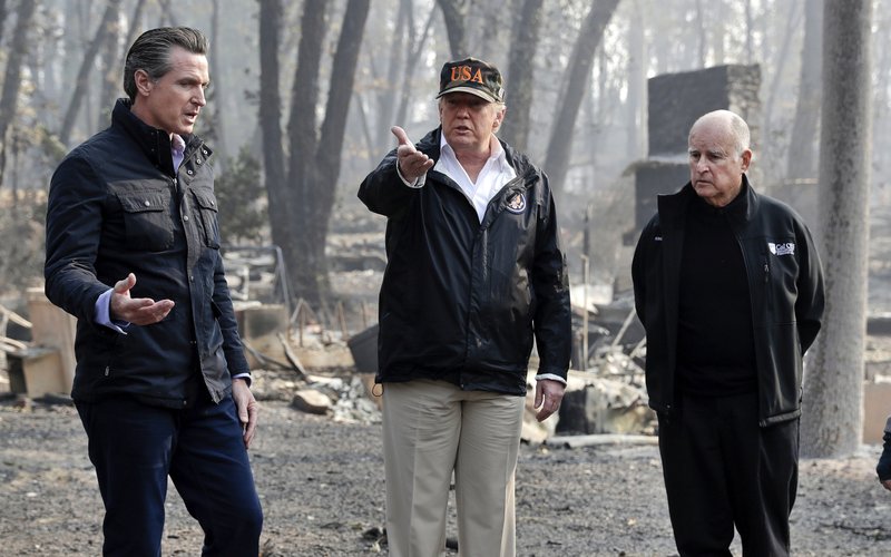 FILE - In this Nov. 17, 2018, file photo, President Donald Trump talks with then Gov.-elect Gavin Newsom, left, and as California Gov. Jerry Brown listens during a visit to a neighborhood impacted by the wildfires in Paradise, Calif. California Gov. Gavin Newsom says the Trump administration is engaging in &quot;political retribution&quot; by trying to take back $3.5 billion granted for the state's high-speed rail project. The Democratic governor says President Donald Trump is reacting to California suing over Trump's emergency declaration to pay for a wall along the U.S.-Mexico border. (AP Photo/Evan Vucci, File)