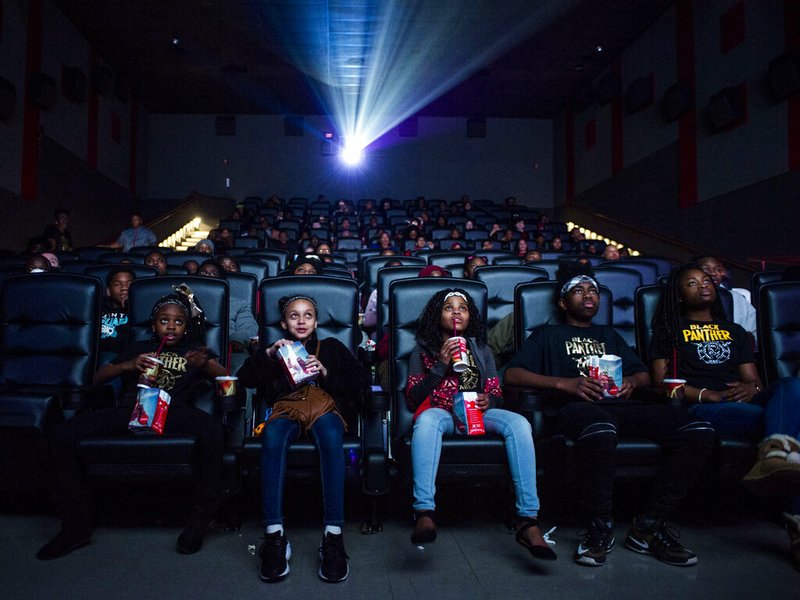 In this Feb. 19, 2018, file photo, Mari Copeny, third from left, watches a free screening of the film "Black Panther" with more than 150 children, after she raised $16,000 to provide free tickets in Flint Township, Mich. Streaming services are starting to catch up on getting the latest movies quickly, yet they are no match for the main attraction of movie theaters: no distractions from Facebook, online chats, household chores and what not. (Jake May /The Flint Journal-MLive.com via AP, File)
