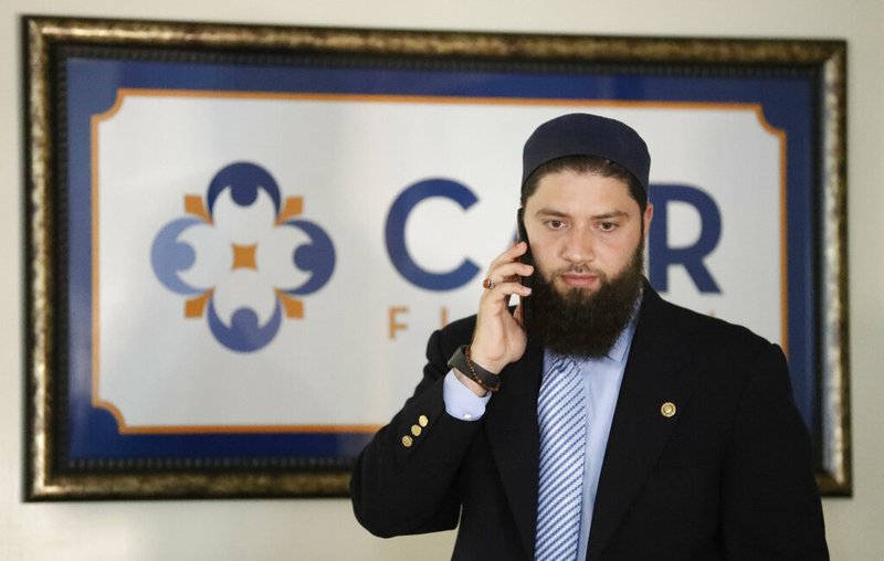 Hassan Shibly, attorney for Hoda Muthana, the Alabama woman who left home to join the Islamic State group in Syria, speaks on a phone before a news conference Wednesday, Feb. 20, 2019, in Tampa, Fla. United States Secretary of State Mike Pompeo said Muthana is not a U.S. citizen and will not be allowed to return to the United States. (AP Photo/Chris O'Meara)